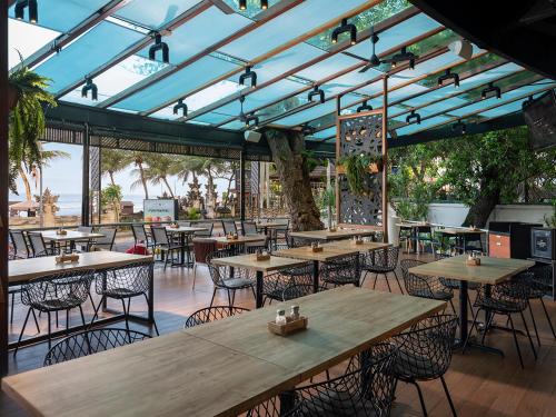 勒吉安Anantara Vacation Club Legian的餐厅设有木桌和椅子以及蓝色的天花板。