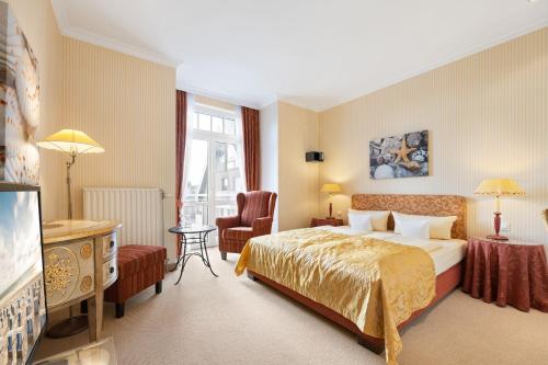 韦斯特兰Strandhotel Sylt GmbH的配有一张床和一把椅子的酒店客房