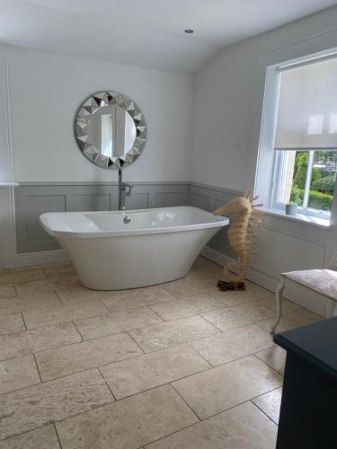 吉夫诺克Giffnock Rooms的浴室设有白色浴缸及镜子