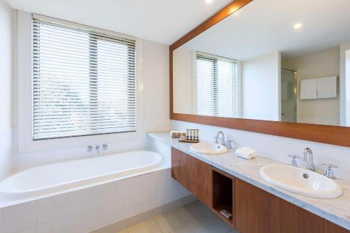 Wonga Park亚拉河谷旅舍的浴室配有2个盥洗盆、浴缸和大镜子