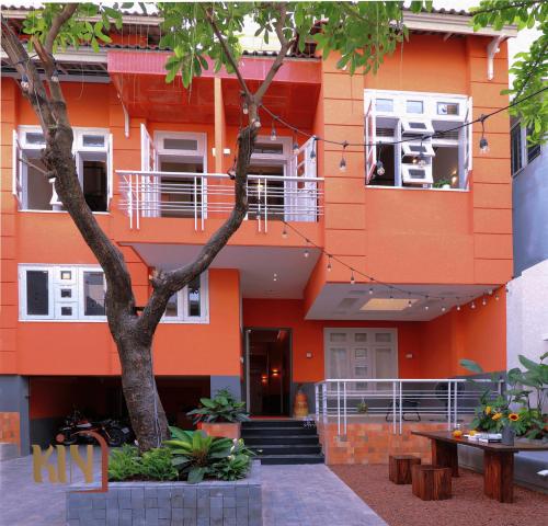胡志明市Kin Wander Tan Quy的一座橘色的建筑,前面有一棵树