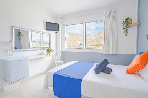 GuazaHostel Neon Tenerife的一间卧室设有一张床、一个窗口和一台电视