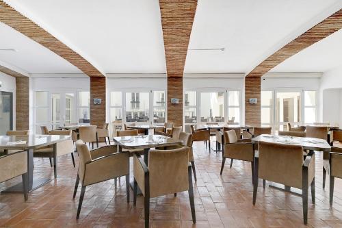 卡武埃鲁Hotel Carvoeiro Plaza的用餐室设有桌椅和窗户。