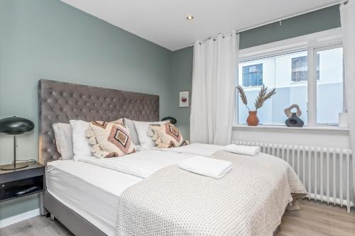 雷克雅未克Venture Vacation-Reykjavík Center, King bed, 65" TV with Netflix的一间卧室配有一张带白色床单的床和一扇窗户。