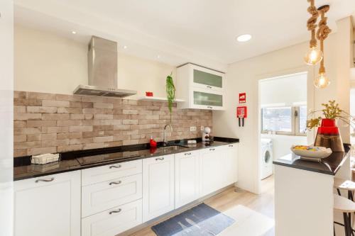 布拉加Apartamento Lírio - Minho's Guest的厨房配有白色橱柜和砖墙