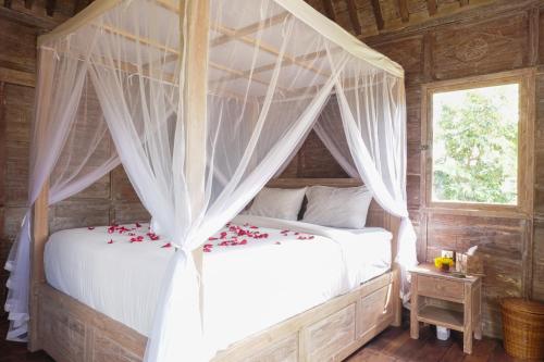 坎古Nunu Bali Eco Friendly Retreat的一间卧室配有带鲜花的天蓬床