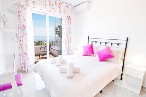 阿罗约德拉迷雅Villa Yolanda del Mar的白色卧室配有带粉红色枕头的大床