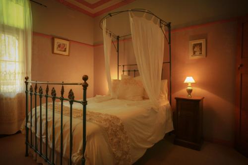 GlenifferFreida - Historic Farmhouse Bellingen的卧室配有带白色床单的天蓬床