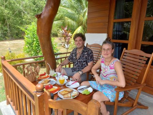 坦加拉Hanguk Lanka Lagoon Villa的坐在餐桌旁吃饭的男人和女人