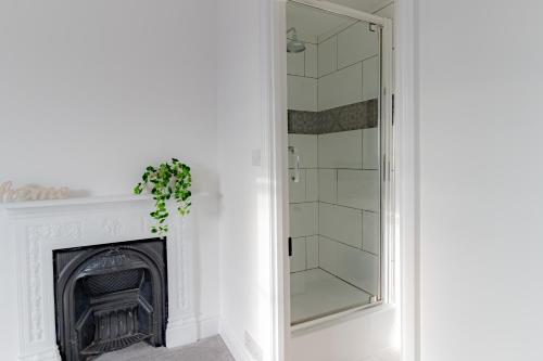 切尔滕纳姆Fabulous, vibrant, town house, central Bath Road的一间带壁炉和玻璃淋浴间的浴室