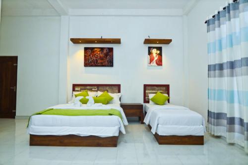 阿努拉德普勒Thinaya lake resort的白色墙壁客房的两张床
