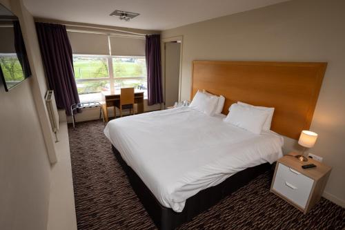 克莱德班克泰坦酒店的酒店客房设有一张大床和一张桌子。