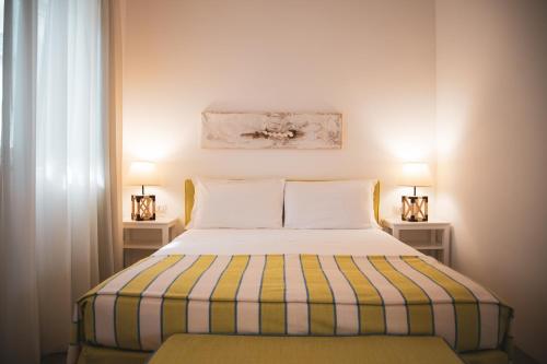 马蒂纳塔安瑞摩乔治酒店的一间卧室配有一张带条纹毯子和两盏灯的床。