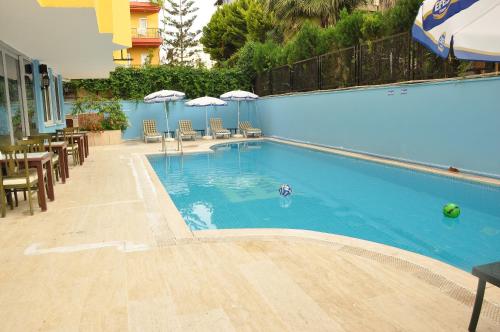 安塔利亚萨瓦酒店的一座带椅子和遮阳伞的游泳池位于一座建筑旁边