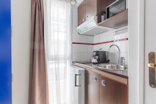 波城Appart'City Confort Pau Centre的一个带水槽和窗户的小厨房