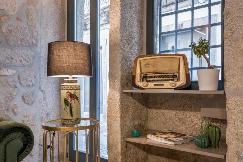 波尔图Ribeira Douro Hotel的一间配有电视的房间和架子上的一台旧收音机
