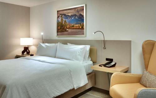 博伊西Hilton Garden Inn Boise Downtown的配有一张床和一把椅子的酒店客房