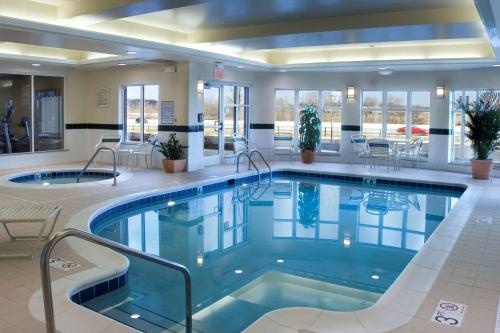 北坎顿阿克伦希尔顿花园酒店-坎顿机场的酒店大堂的游泳池,配有桌椅
