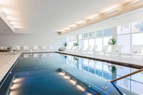 达拉斯达拉斯市中心汉普顿酒店及套房的一座带白色椅子的大型游泳池