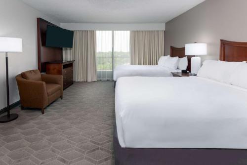 达拉斯达拉斯中央公园区希尔顿合博套房酒店的酒店客房,配有两张床和椅子
