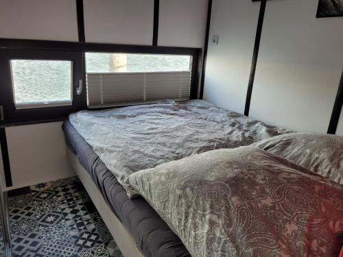 费马恩Houseboat of Grimm的一张小床,位于带两个窗户的房间