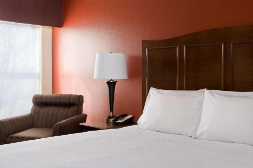 拉伯克拉伯克汉普顿酒店的一间卧室配有一张床、一把椅子和一盏灯