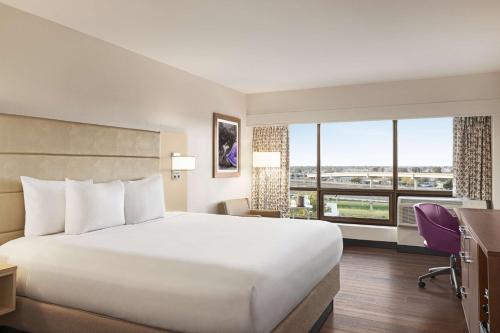 肯纳新奥尔良机场希尔顿逸林酒店的一间酒店客房,设有一张大床和一个大窗户