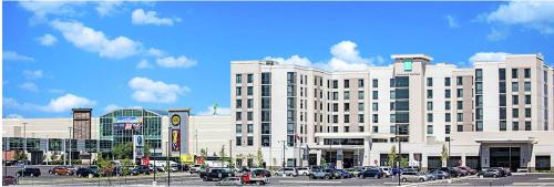 锡拉丘兹Embassy Suites By Hilton Syracuse Destiny USA的一座白色的大建筑,汽车停在停车场