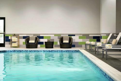 锡拉丘兹Embassy Suites By Hilton Syracuse Destiny USA的游泳池位于酒店带椅子的房间内