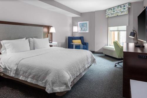 阿林顿Hampton Inn & Suites Arlington Crystal City DCA的配有一张床和一把椅子的酒店客房