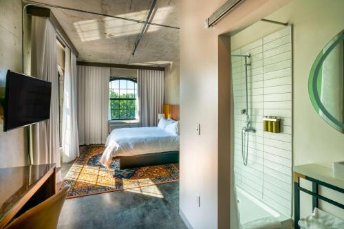沃里克NYLO Providence Warwick Hotel, Tapestry Collection by Hilton的一间卧室设有一张床和一个步入式淋浴间。