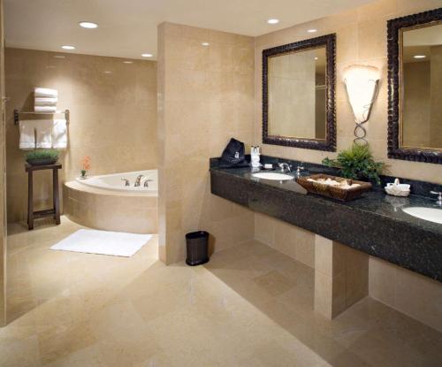 皮奥里亚东皮奥里亚希尔顿合博套房酒店&湖畔会议中心的浴室设有2个水槽、浴缸和镜子