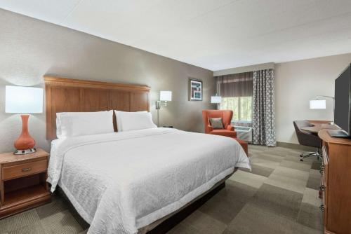 丹伯里丹伯里汉普顿酒店的酒店客房带一张大床和一把椅子