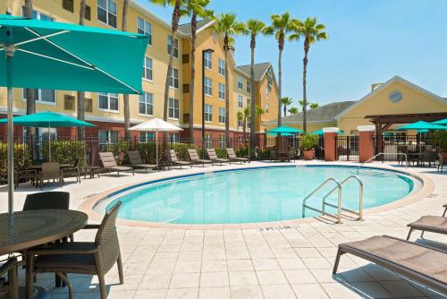 奥兰多奥兰多UCF区希尔顿惠庭套房酒店的酒店设有带桌椅和遮阳伞的游泳池。
