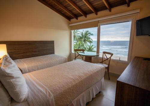 马利西亚斯Amora Hotel Maresias的一间带两张床的卧室,享有海景
