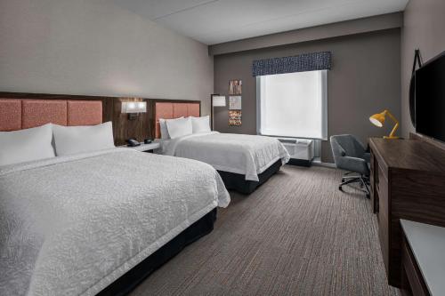 沃本Hampton Inn Boston Woburn的酒店客房设有两张床和一台平面电视。