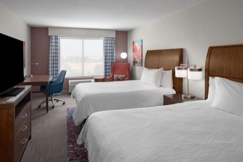 盐湖城盐湖城机场希尔顿花园酒店 的酒店客房设有两张床、一张桌子和一台电视。