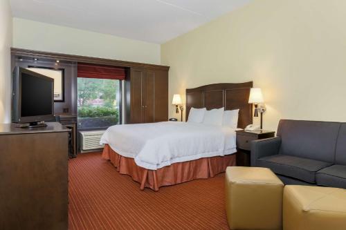 乌尔班纳尚佩恩/厄巴纳希尔顿恒庭酒店的酒店客房配有床、沙发和电视。