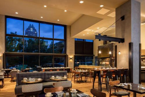 奥斯汀奥斯汀希尔顿酒店的餐厅设有桌椅和大窗户。