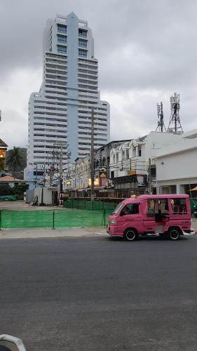 芭东海滩PATONG TOWER DESIGNER's APARTMENTS by PATONG TOWER AGENCY的停在街道边的粉红色货车