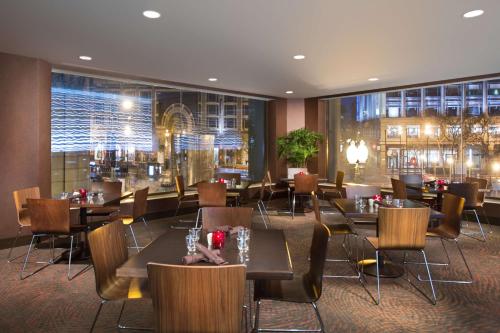 旧金山55旧金山联合广场希尔顿公园酒店的餐厅设有桌椅和大窗户。