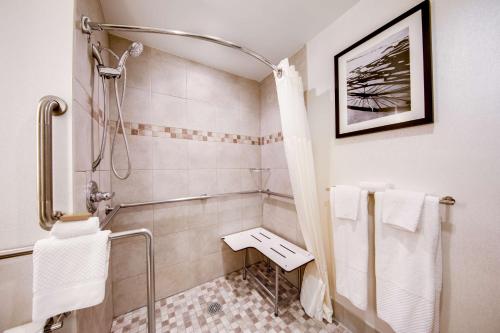 泽西市泽西市希尔顿双树套房酒店的带淋浴和白色毛巾的浴室