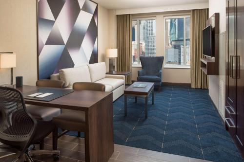 西雅图西雅图市中心先锋广场希尔顿合博套房酒店的一间客厅,客厅配有沙发和一张书桌,位于酒店的房间