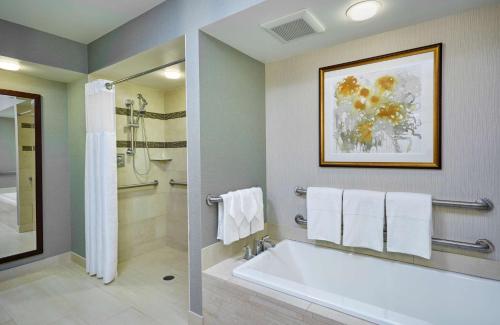 阿林顿华盛顿特区水晶城希尔顿逸林酒店的浴室配有白色浴缸和淋浴。