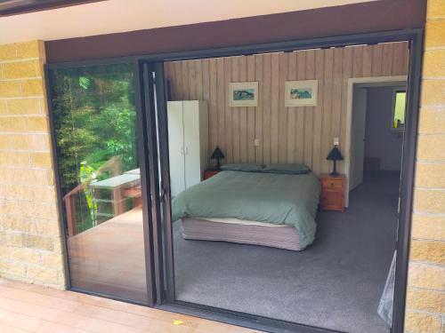 纳尔逊Maitai Whare Iti - Adventure Cabins & House的一间卧室设有一张床和一个滑动玻璃门