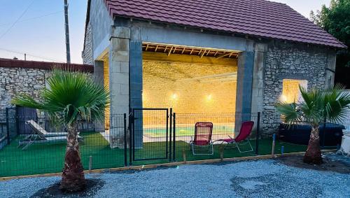 若奈克朗maison chaleureuse ,avec piscine, spa, Futuroscope的建筑前有两棵棕榈树的围栏