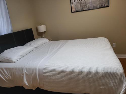 金斯顿Lovely Place的卧室内的一张带白色床单和枕头的床