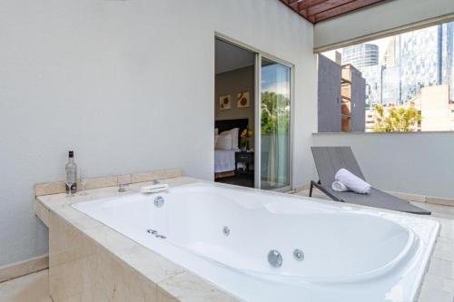 墨西哥城Suites Giorgio的带窗户的浴室内的白色大浴缸