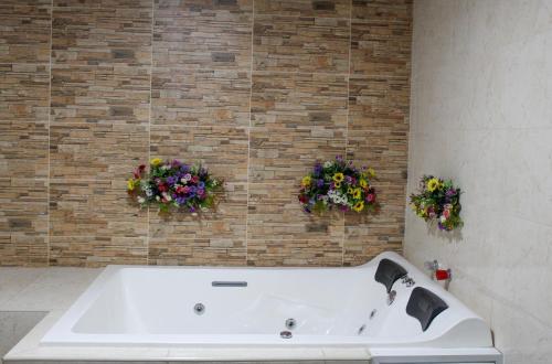 希龙Hotel Colonial San Felipe的砖墙上花卉浴室内的浴缸