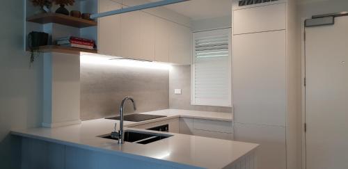 芒格努伊山中庭公寓式酒店的厨房配有白色橱柜和水槽
